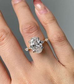 a woman's hand with a diamond ring on top of her finger and an engagement band