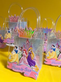 small plastic bags with princesses on them sitting on a yellow tableclothed surface