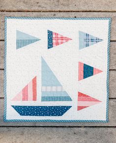 a quilted wall hanging on the side of a brick building with red, white and blue triangles