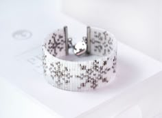 a close up of a bracelet on top of a white box with two silver rings