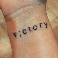 a wrist tattoo with the word victory written on it