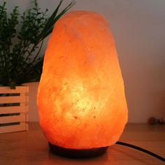 a himalayan salt lamp sitting on top of a wooden table next to a potted plant