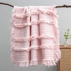 a white blanket hanging on a clothes line next to a wooden cabinet with a plant in it