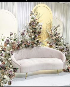 a white couch with flowers on it in front of a mirror and curtained wall