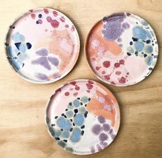 three plates with different designs on them sitting on a wooden counter top next to each other