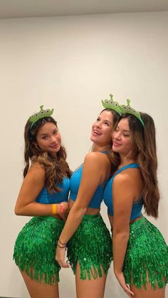 three young women in green and blue outfits posing for the camera with their arms around each other