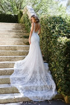 a woman in a wedding dress standing on some steps with her back to the camera