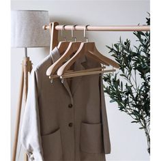 a coat hanging on a clothes rack next to a lamp