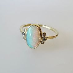 a ring with an oval shaped opal surrounded by small diamonds on the bottom and sides