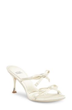 a woman's white high heeled sandal with an ankle strap and bow detail