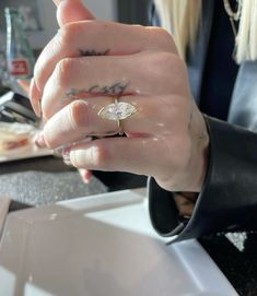 a close up of a person wearing a ring on their finger and holding something in the other hand