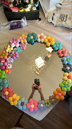 a person taking a photo in front of a mirror with balloons on the table and confetti around it