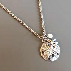 Small Sand Dollar Necklace - This is a smaller version of my other Sand Dollar necklace. The Sand Dollar is accented with a a Silver Pewter Starfish and White Freshwater Pearl. The Sand Dollar is approximately 17mm (slightly smaller than an US dime) and has a hollow back. Stainless Steel Chain For other Sand Dollar Necklaces: https://www.etsy.com/shop/mcstoneworks?search_query=sand+dollar+necklace Silver Charm Necklace For Beach, Silver Charm Necklaces For Beach, Silver Starfish Jewelry For Vacation, Silver Jewelry With Starfish Charm For The Beach, Adjustable Silver Charm Necklace For Beach, Adjustable Silver Charm Necklace For The Beach, Adjustable Silver Starfish Necklace, Silver Adjustable Starfish Necklace, Silver Dragonfly Necklace