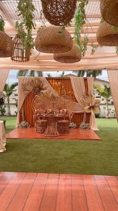 an outdoor wedding setup with white drapes and wicker baskets hanging from the ceiling