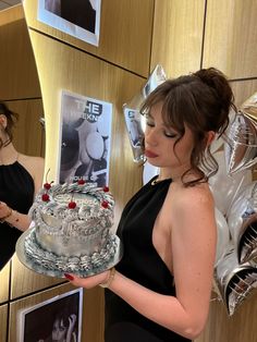 a woman in a black dress holding a cake