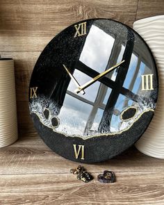 a clock that is sitting on top of a wooden table next to some cups and saucers