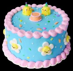 a blue cake with pink frosting and two yellow ducks on top