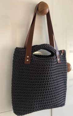 a handbag hanging on the wall with a wooden handle