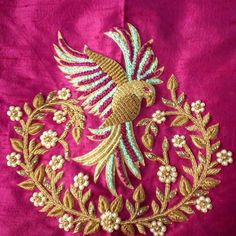 an embroidered bird on a pink fabric with gold trimmings and pearls in the center