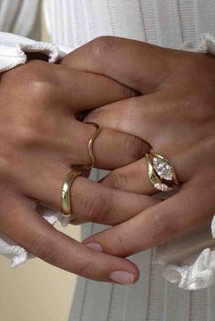 two women's hands with wedding rings on their fingers, both holding each other