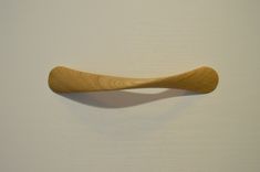 a wooden object hanging on the wall with white walls in the background and light colored wood