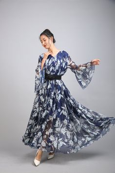 a woman in a blue and white floral print dress is posing for the camera with her arms outstretched