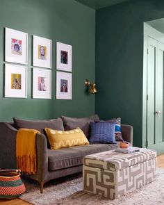 a living room with green walls and pictures on the wall, including a gray couch