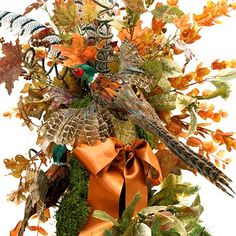 an arrangement of autumn leaves and birds in a vase with orange ribbon on white background