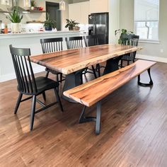 a wooden table with black chairs and a bench in the middle of a living room