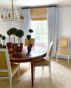 a dining room table with chairs and potted plants on it in front of a window