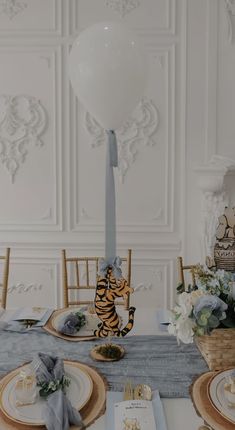 the table is set with plates, silverware and an air balloon in the shape of a tiger