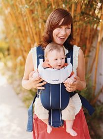 a woman is holding a baby in a carrier