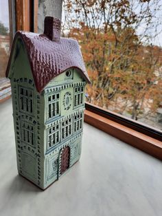 a small green house sitting on top of a window sill