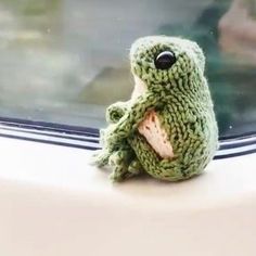 a stuffed frog sitting on top of a window sill