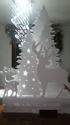 a white christmas tree with deer and stars on it in front of a mirror that is lit up