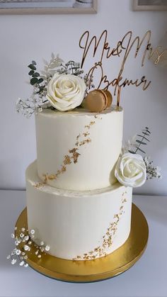 a wedding cake with white flowers and gold lettering