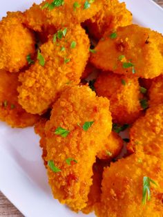 some fried food on a white plate with parsley sprinkled over the top