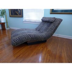 a leopard print chaise lounge chair sitting on top of a hard wood floor next to a window