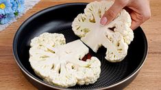 someone is cutting cauliflower into pieces in a skillet on a wooden table