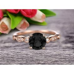 an oval black diamond ring with two diamonds on the band and a flower bouquet in the background