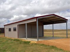 a small metal building in the middle of an open field with grass and dirt around it