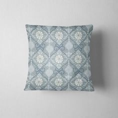 a blue and white pillow with an intricate pattern on it, sitting against a wall