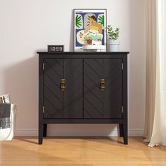 a black cabinet with gold handles in a white living room, next to a window