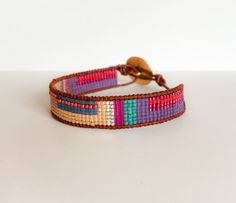 a bracelet with multicolored beads and a gold clasp on a white table top