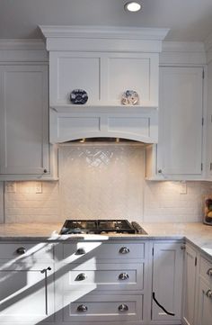 a kitchen with white cabinets and marble counter tops is pictured in this image, the light shines on the stove