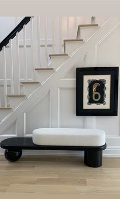 a black bench sitting in front of a stair case next to a white bannister