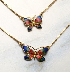 "These beautiful 18ct gold butterfly necklaces are enhanced with enamel in reds and blues. They're mounted on 18ct gold box chains that measure 15\" long. The larger one is 21mm wide and weighs 4.6 grams, the smaller is 16mm wide but is a little thicker and so weighs 5.4 grams. They were originally bought in the Middle East and are marked as 18ct gold on the chain tags. They're finished as new and so would be suitable as gifts. PLEASE NOTE: The large one has sold now so only the smaller one is a Gold Enamel Jewelry With Butterfly Charm, Multicolor Butterfly Print Jewelry Gift, Gold Jewelry With Butterfly Print For Gift, Gold Butterfly Print Jewelry For Gift, Red Butterfly Charm Necklace, Red Butterfly Necklace For Gift, Butterfly Necklaces, Wedding Ring Finger, Butterfly Necklace Gold