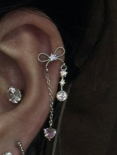 a person wearing ear piercings with cross and heart charms attached to the side of their ear