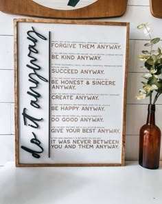 a wooden sign sitting on top of a table next to a vase filled with flowers