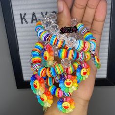 a hand holding several bracelets with smiley faces on them and rainbow beads around the wrist